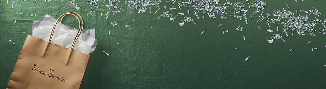 Brown paper bag with handles on a green surface with scattered white items.