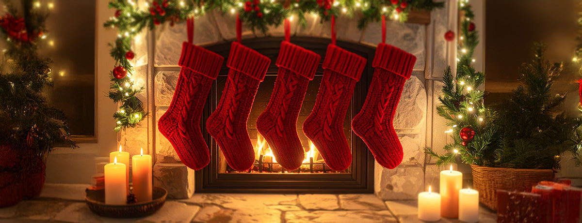 Red stockings hanging above a fireplace with Christmas decorations.